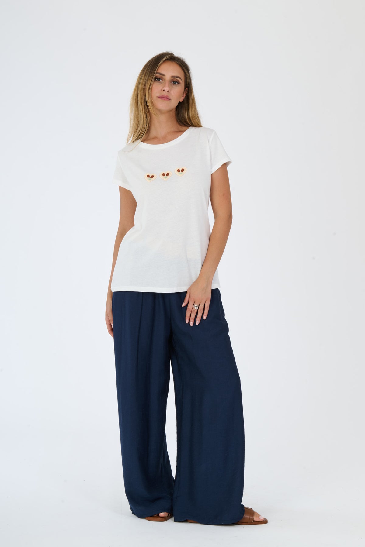 Donna con un completo bianco: t-shirt e pantaloni larghi, abbinati a sandali