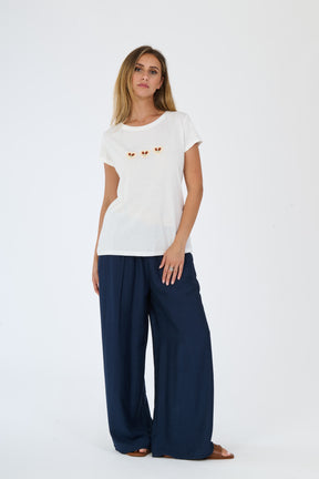 Donna con un completo bianco: t-shirt e pantaloni larghi, abbinati a sandali