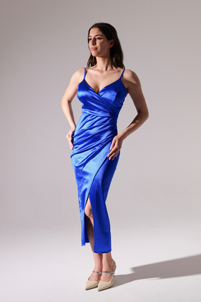 Donna in abito blu scuro satinato, spalline sottili, gonna con aperto laterale, posa elegante