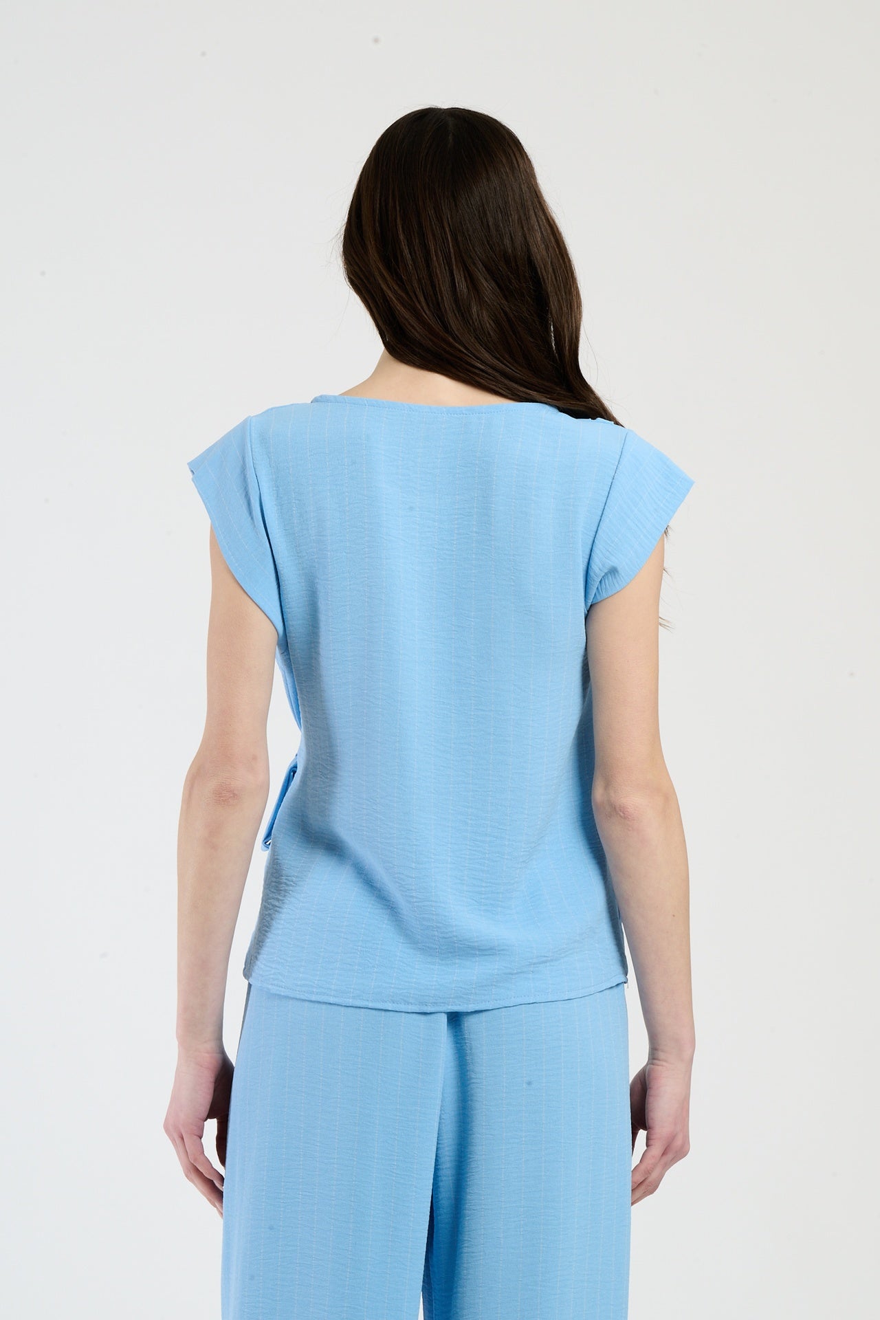 Donna in set azzurro con top a nodo, combinazione accattivante per l’estate.