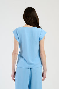 Donna in set azzurro con top a nodo, combinazione accattivante per l’estate.