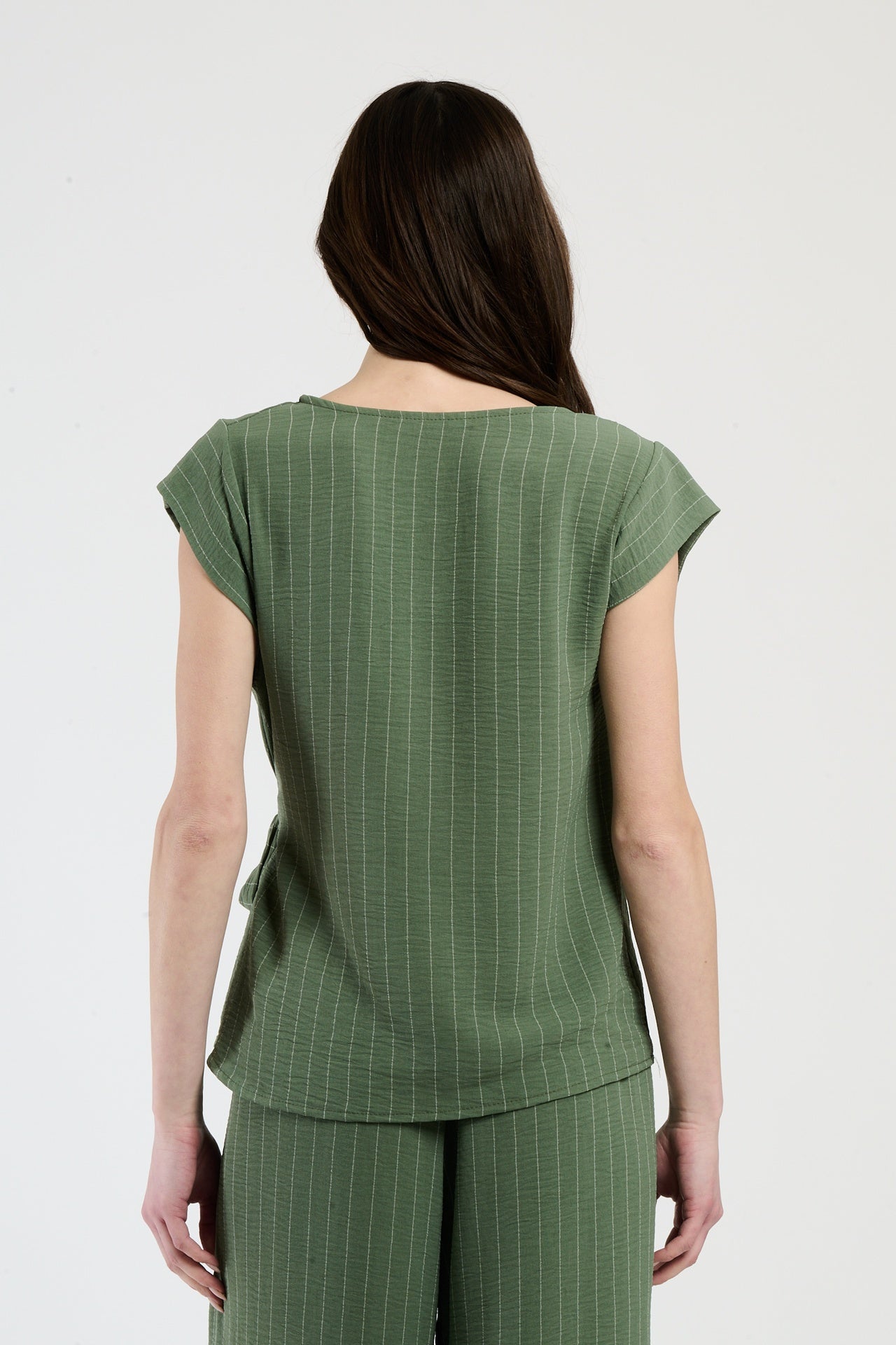 Donna in set militare con top a nodo, combinazione audace per uno stile unico.