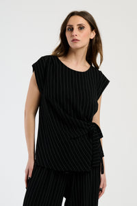 Donna in set nero con top a nodo, combinazione impeccabile per serate notturne.