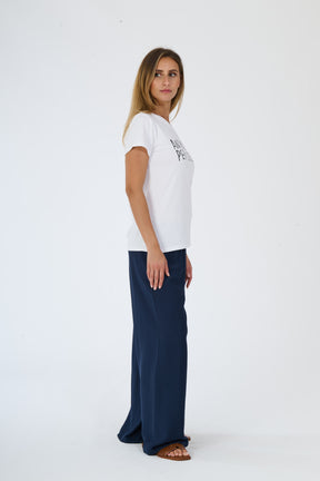 Donna indossa t-shirt bianca decorata e pantaloni scuri fluidi