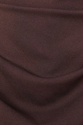 Donna indossa un abito marrone senza maniche, lunghezza midi, con nodo al petto, look elegante.