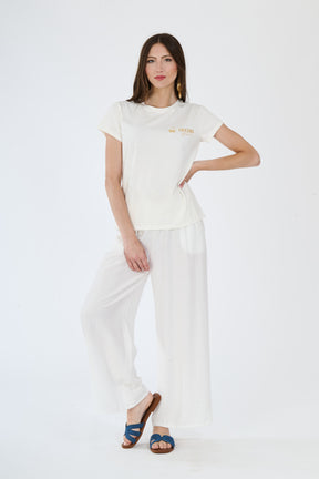 Donna indossa un outfit bianco composto da t-shirt e pantaloni fluidi