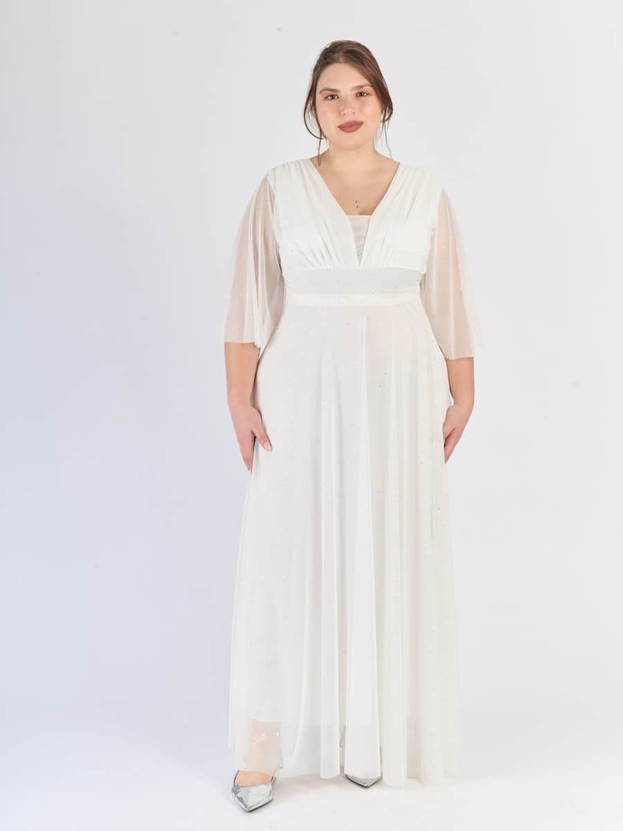 Lungo abito bianco romantico, scollatura a V profonda e maniche chiare, per un’atmosfera angelica.