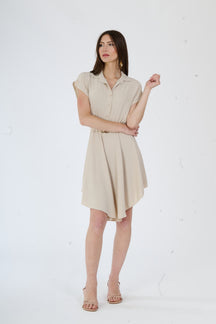 Vestito beige a camicia con taglio asimmetrico e bottoni frontali, ideale per un look sofisticato.