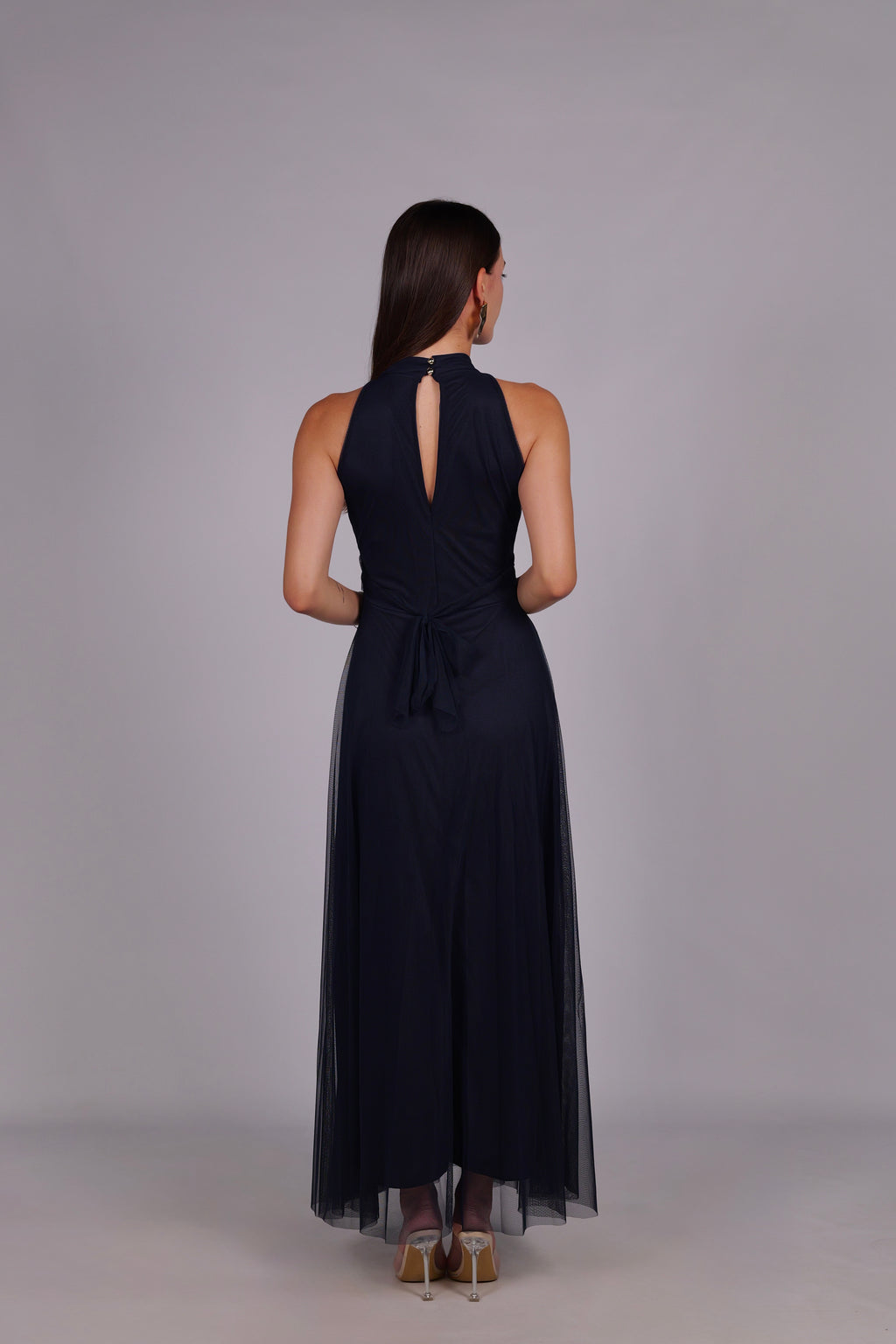 Modella con abito navy a gonna lunga, collo a imbarcatura, foulard in tulle trasparente, outfit sofisticato per eventi.
