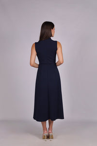 Modella con abito navy a gonna midi, senza maniche, nodo al petto, outfit sofisticato.