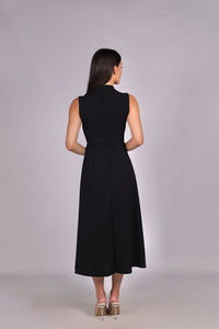 Modella con abito nero a gonna midi, senza maniche, nodo al petto, outfit chic.