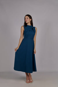 Modella con abito ottanio a gonna midi, senza maniche, design con nodo al petto, outfit elegante.