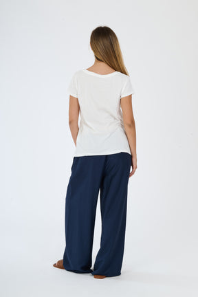 Modella in abbigliamento beige: t-shirt a maniche corte e pantaloni fluidi