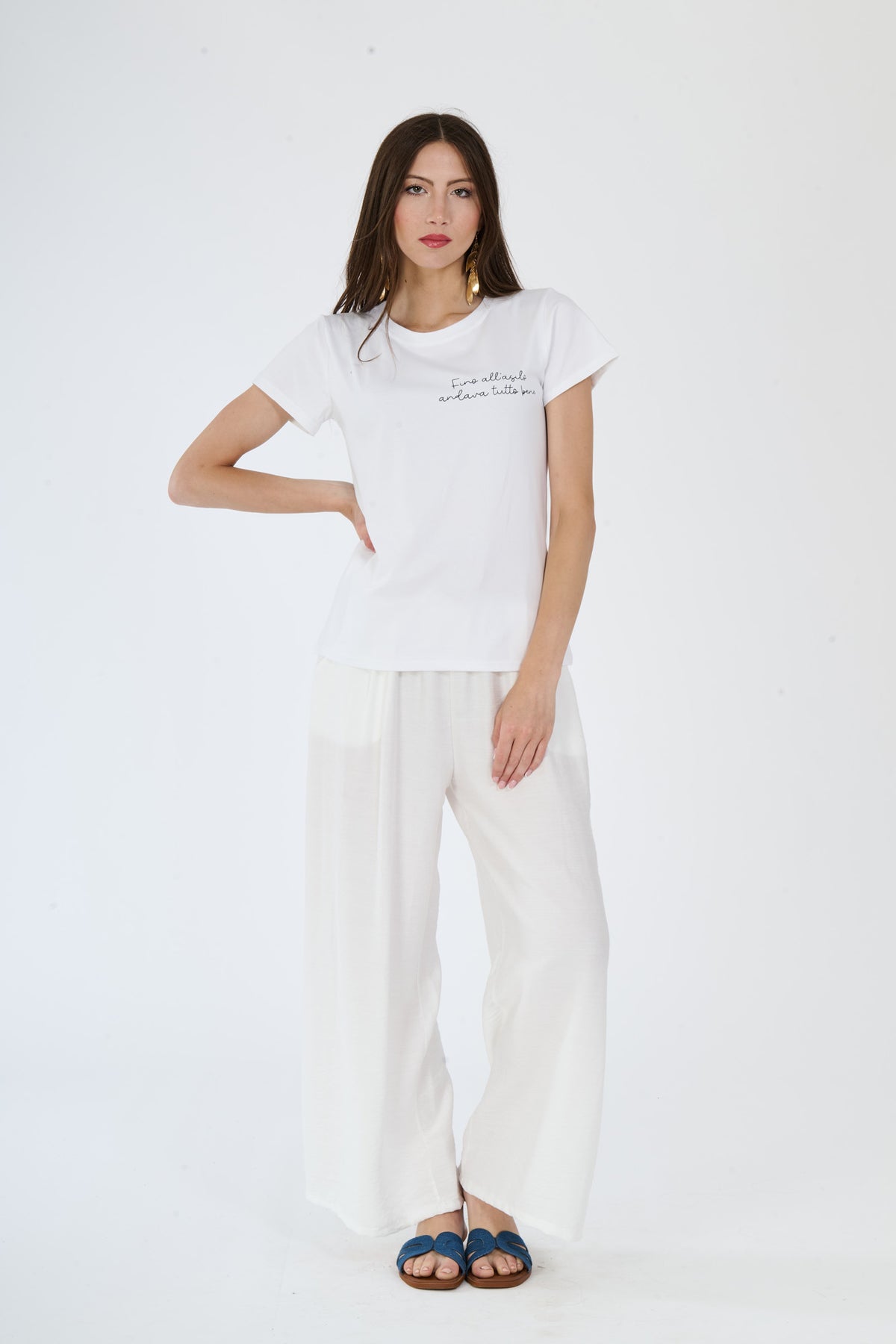 Outfit estivo bianco: t-shirt e pantaloni larghi presentati da una ragazza