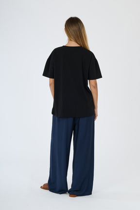 Outfit nero e scuro: t-shirt beige e pantaloni larghi scuri su una figura