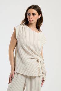 Set beige su donna: top senza spalline e pantaloni, tonalità neutra e rassicurante.