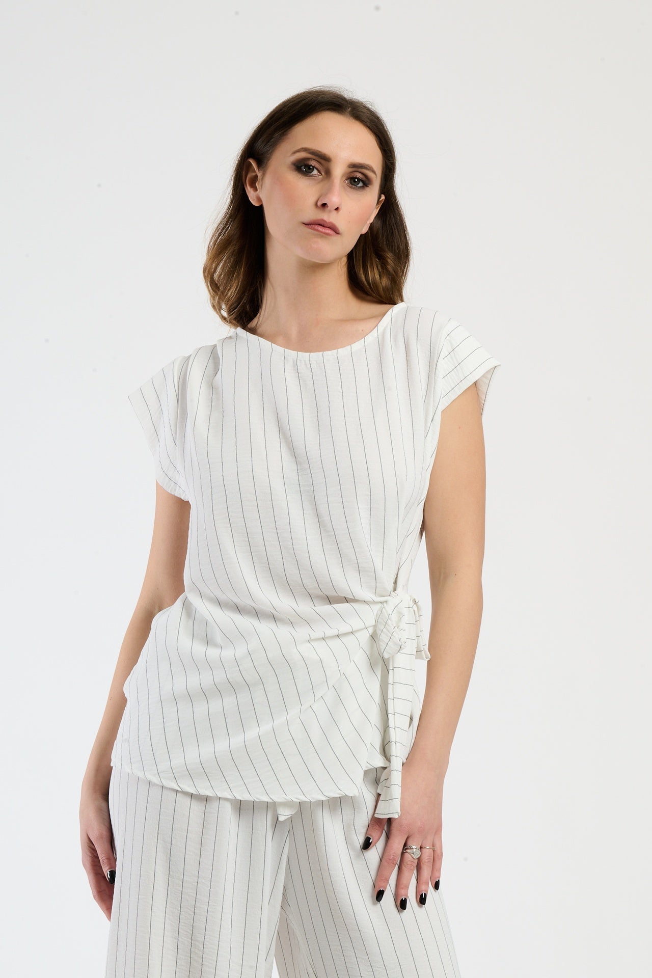 Set bianco su donna: top senza spalline e pantaloni, luminosità e purezza.