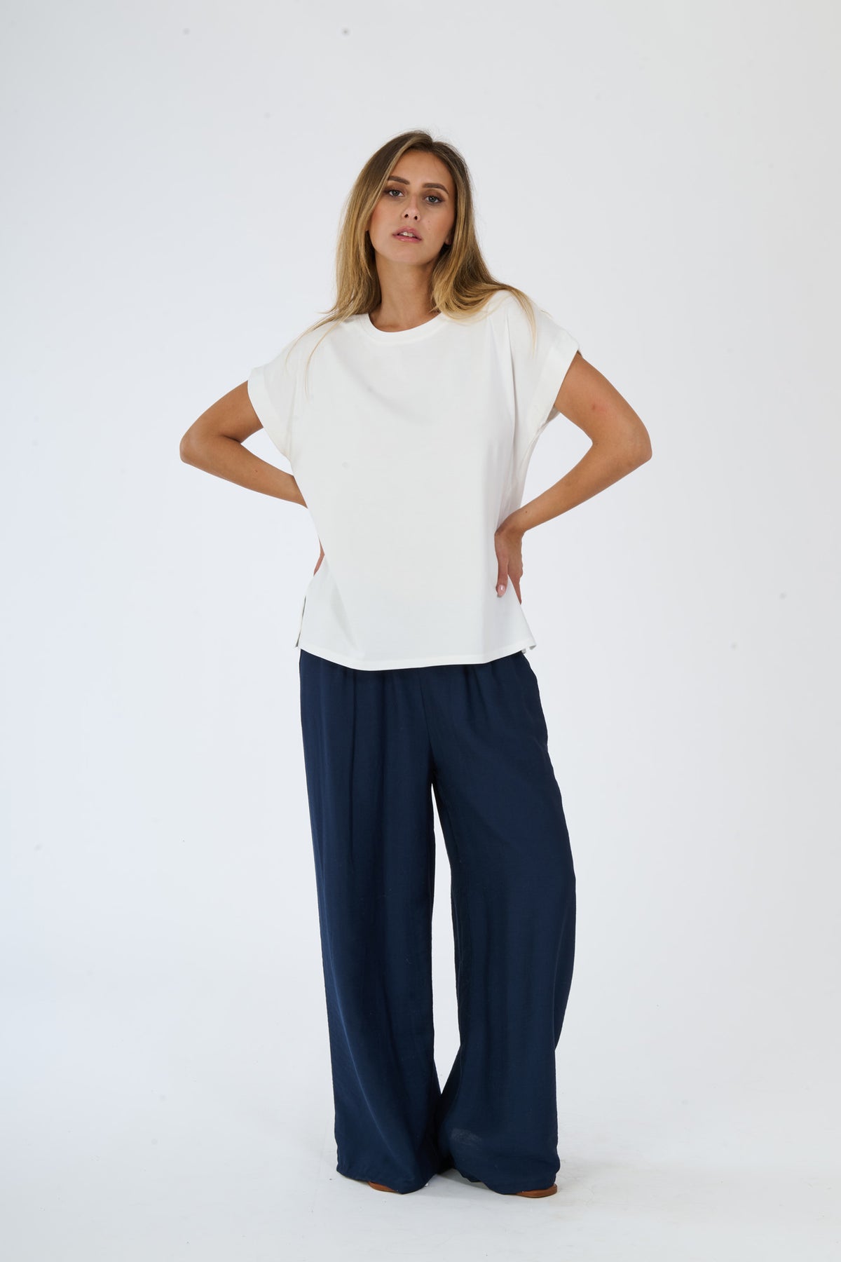 T-shirt beige stampata e pantaloni bianchi larghi su una figura femminile