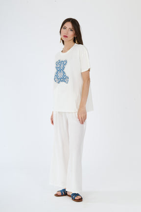 T-shirt bianca con scritta e pantaloni bianchi larghi indossati da una moda