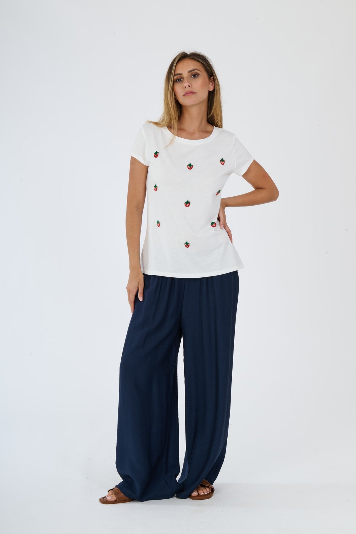 T-shirt bianca con logo e pantaloni bianchi larghi indossati da una donna