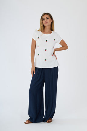 T-shirt bianca con logo e pantaloni bianchi larghi indossati da una donna