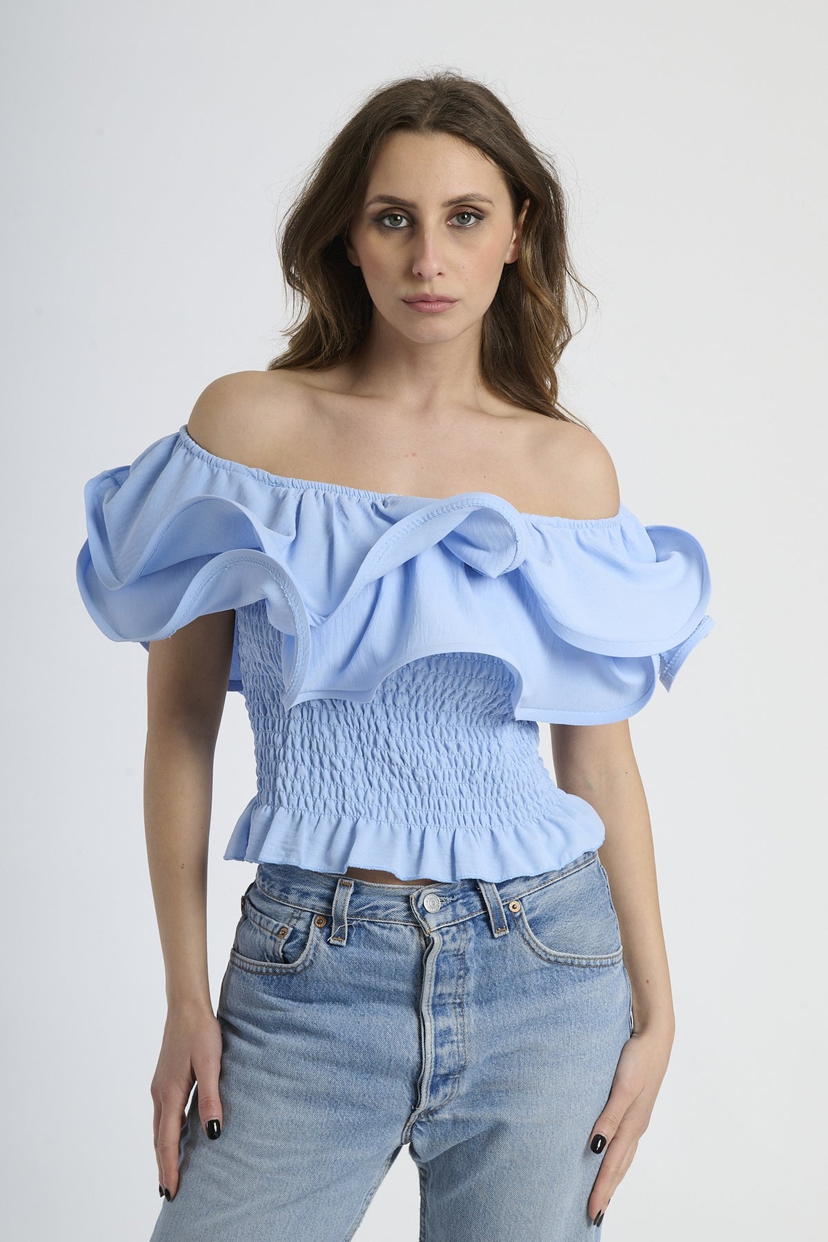 Top azzurro a spalline nude con rouches sul busto, abbinato a jeans.