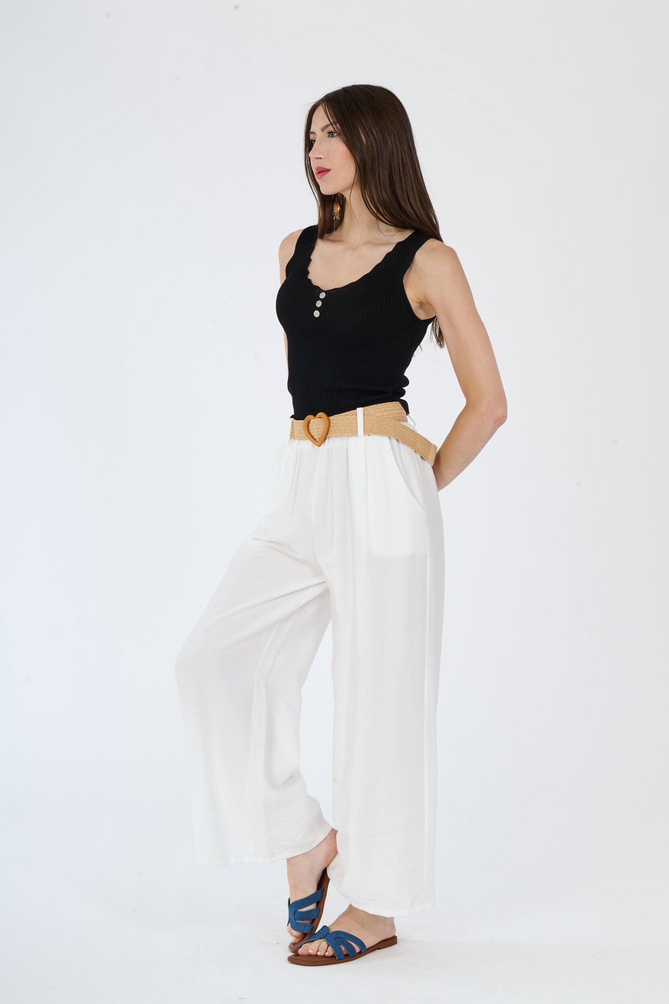 Top nero senza maniche e pantaloni larghi bianchi, un abbinamento che contrasta tenebre e luminosità con classe.