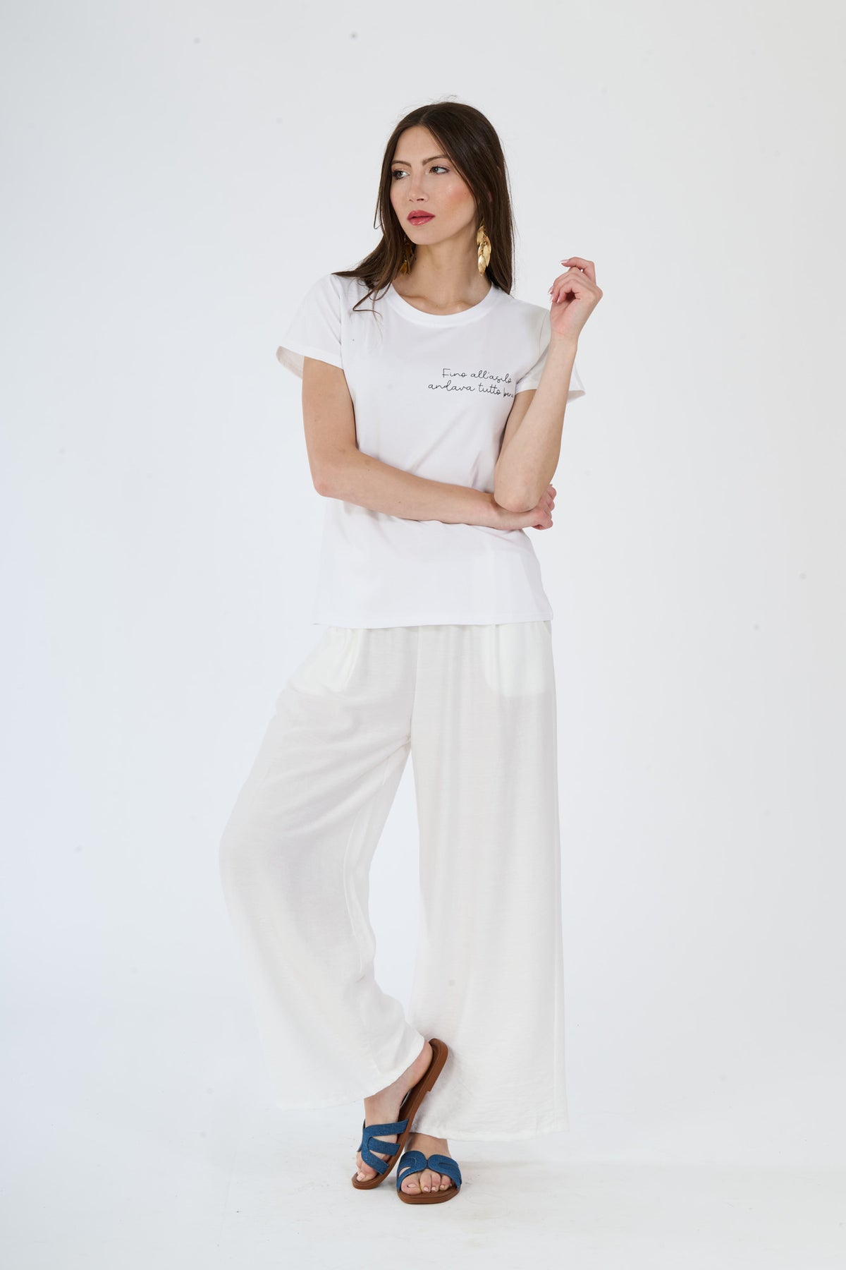 Immagine di una donna con abbigliamento bianco: t-shirt e pantaloni fluidi