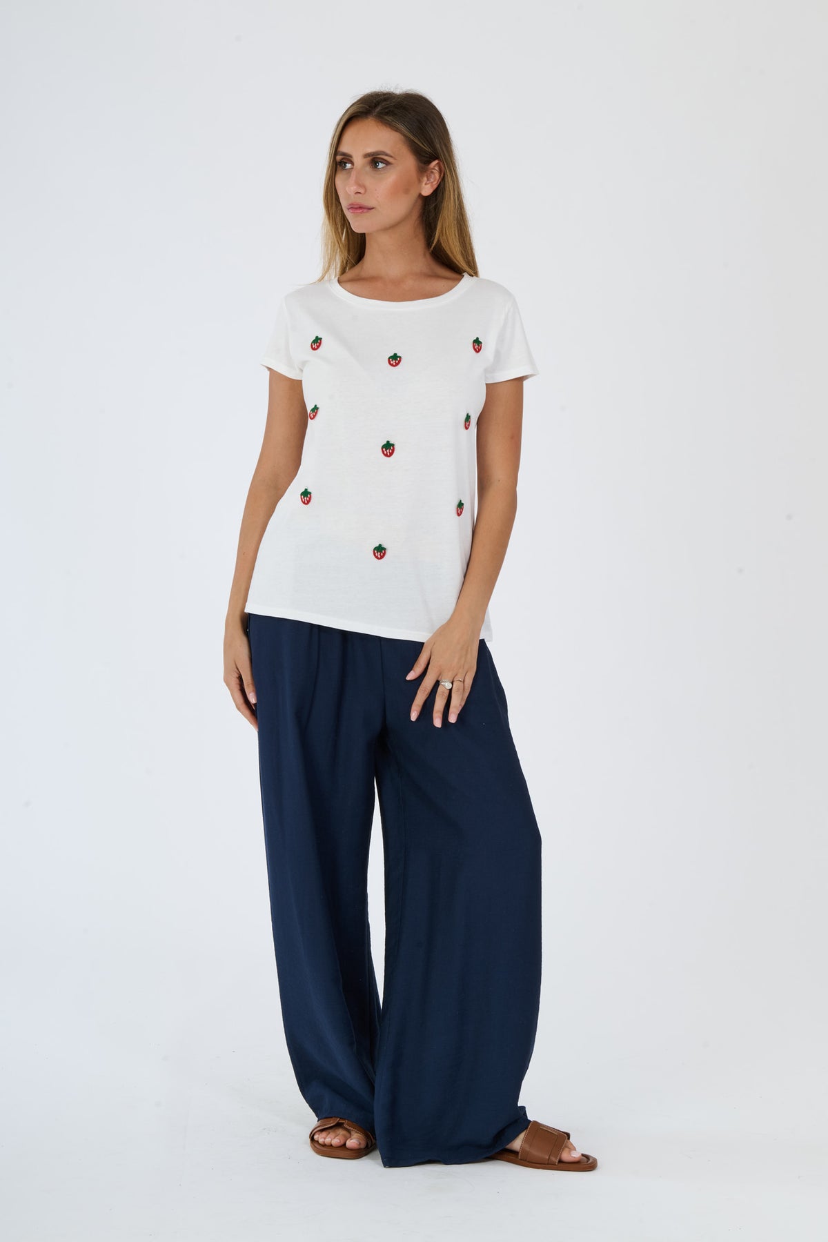 Modella con completo bianco: t-shirt e pantaloni, accessori con sandali blu