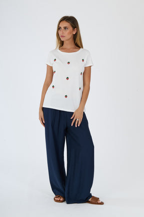 Modella con completo bianco: t-shirt e pantaloni, accessori con sandali blu