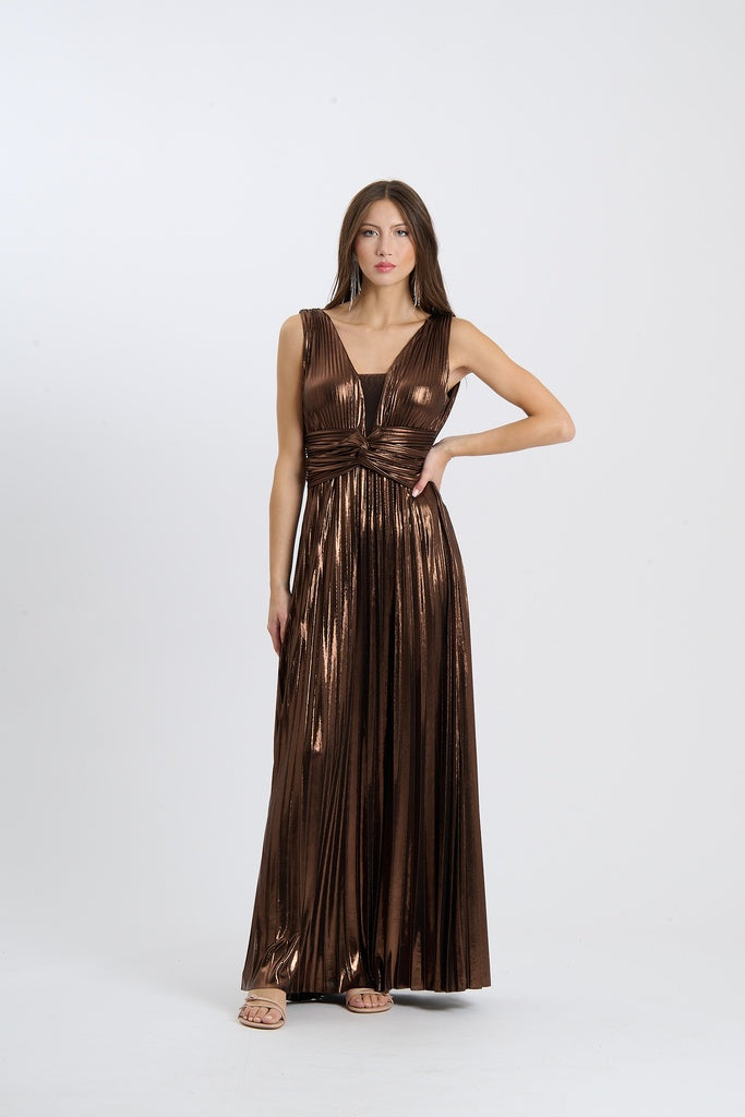 Una donna indossa un abito da sera lungo senza maniche di colore marrone con plissé e scollatura a V, su sfondo chiaro.
