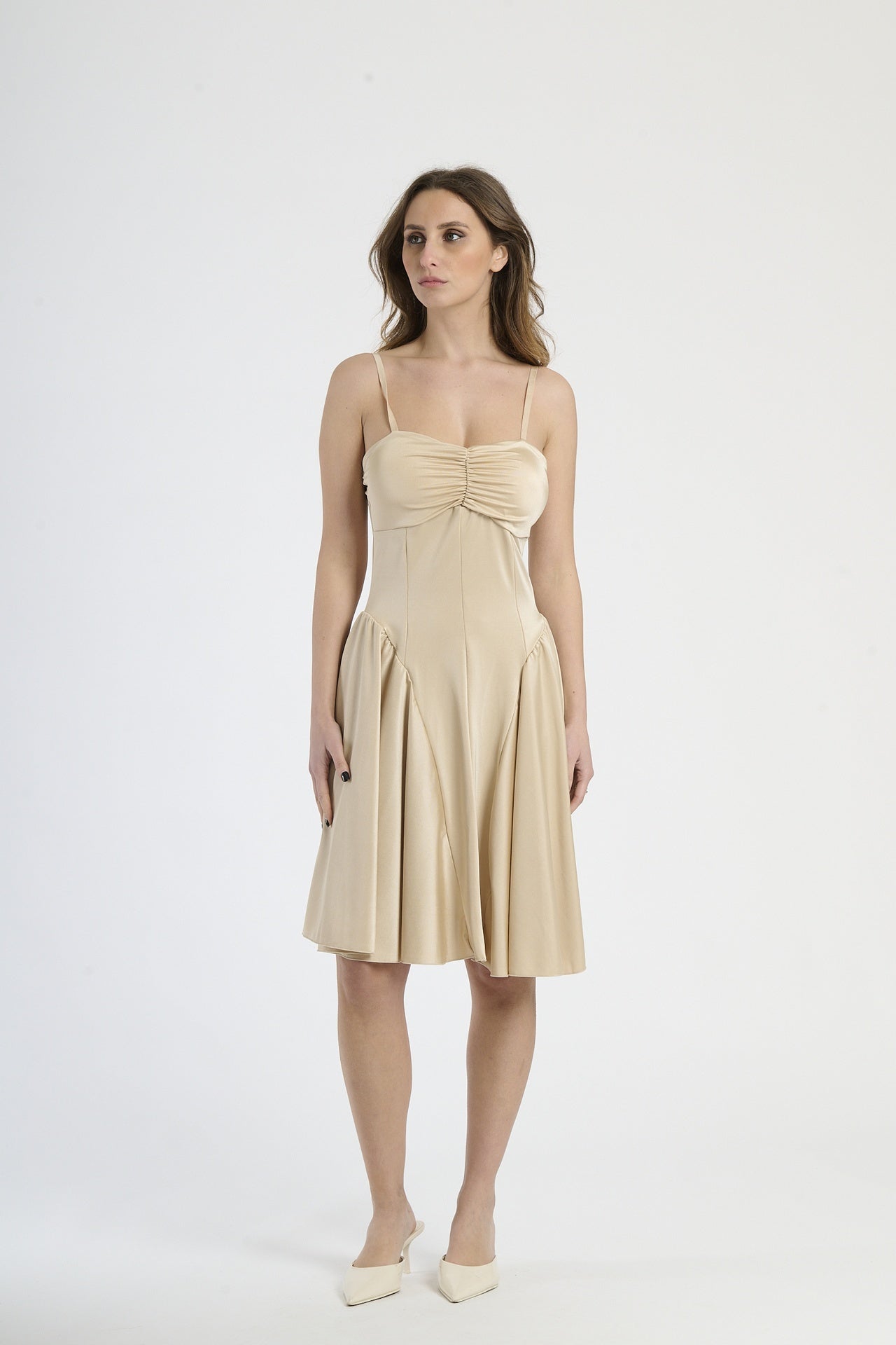 Donna con abito beige a spalline, calore e sofisticatezza neutra.