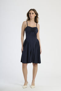 Donna con abito navy a spalline, eleganza classica e impatto visivo.