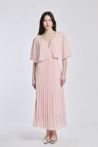 Un abito in rosa con lo stesso design crociato e maniche a mantello, creando un'atmosfera di giovinezza e vitalità.