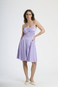 Donna con abito lilla a spalline, originalità e charme soffice.