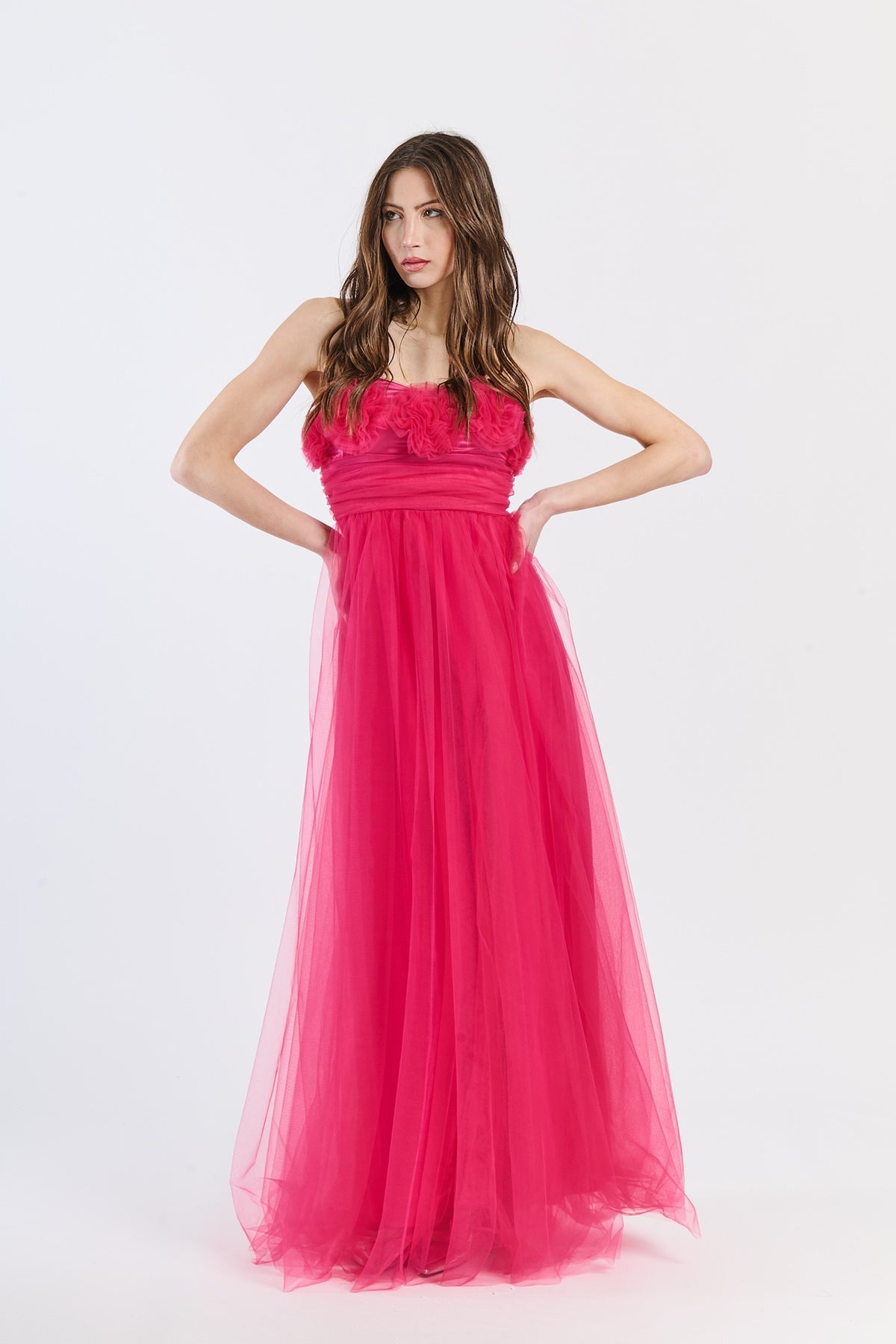 Abito romantico fuxia in tulle luminoso, scollo a barca e drappeggi accesi, perfetto per shoot glamour e serate estive