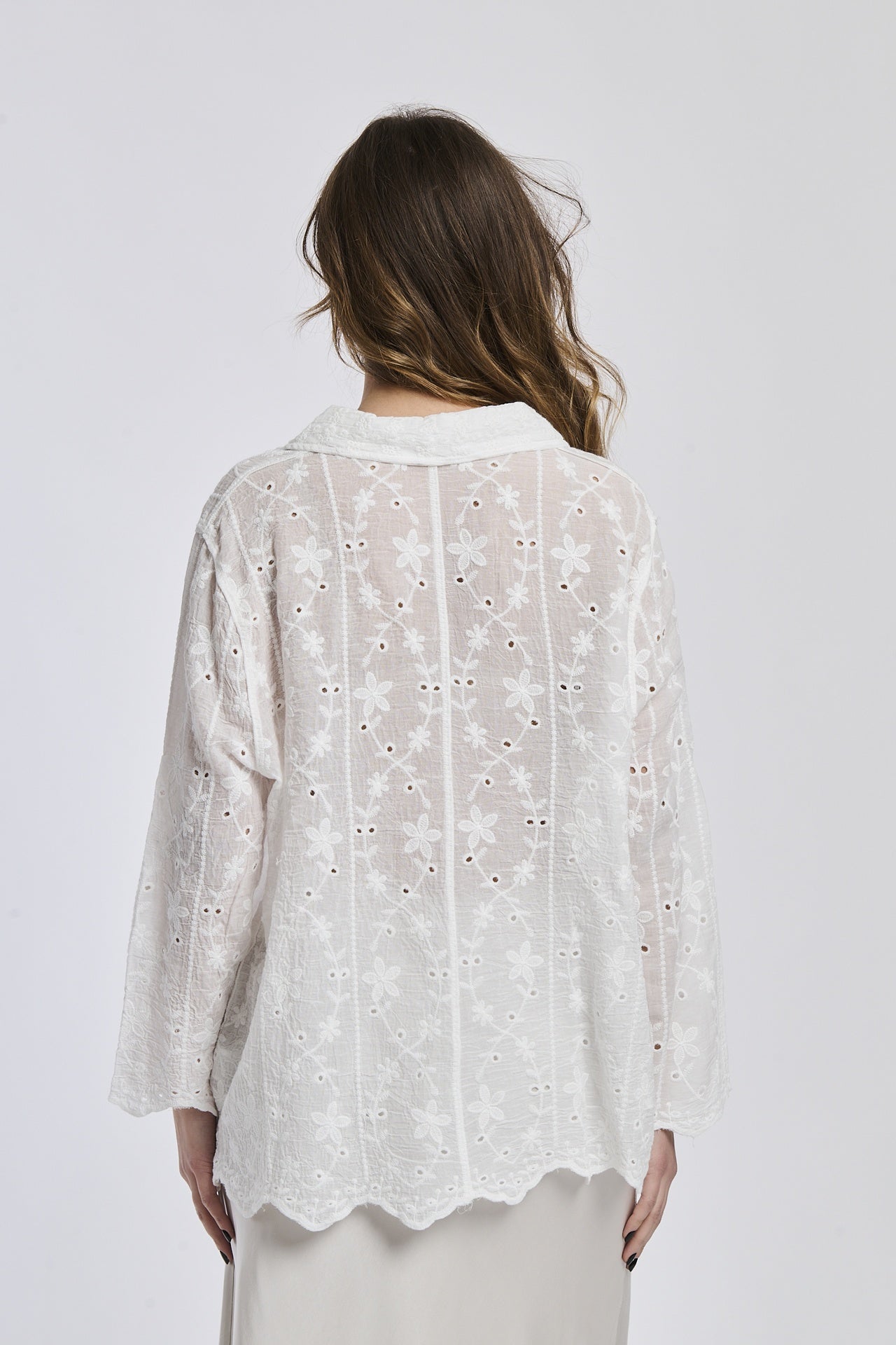 Camicia oversize bianca con motivi floreali, abbinata a gonna bianca, posa semplificata