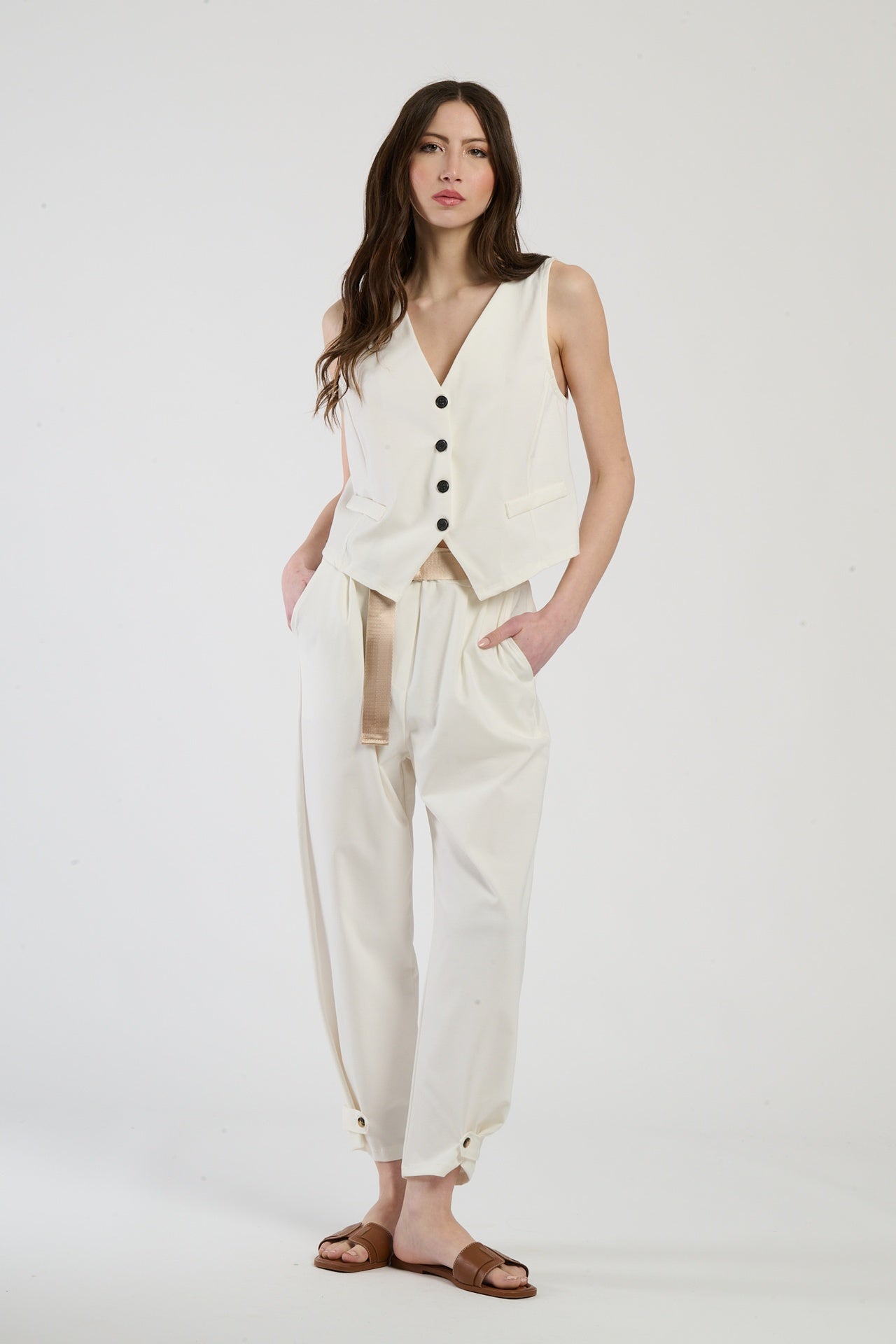 Completo bianco su una modella: gilet a bottoni e pantaloni, combinazione limpida e accattivante.