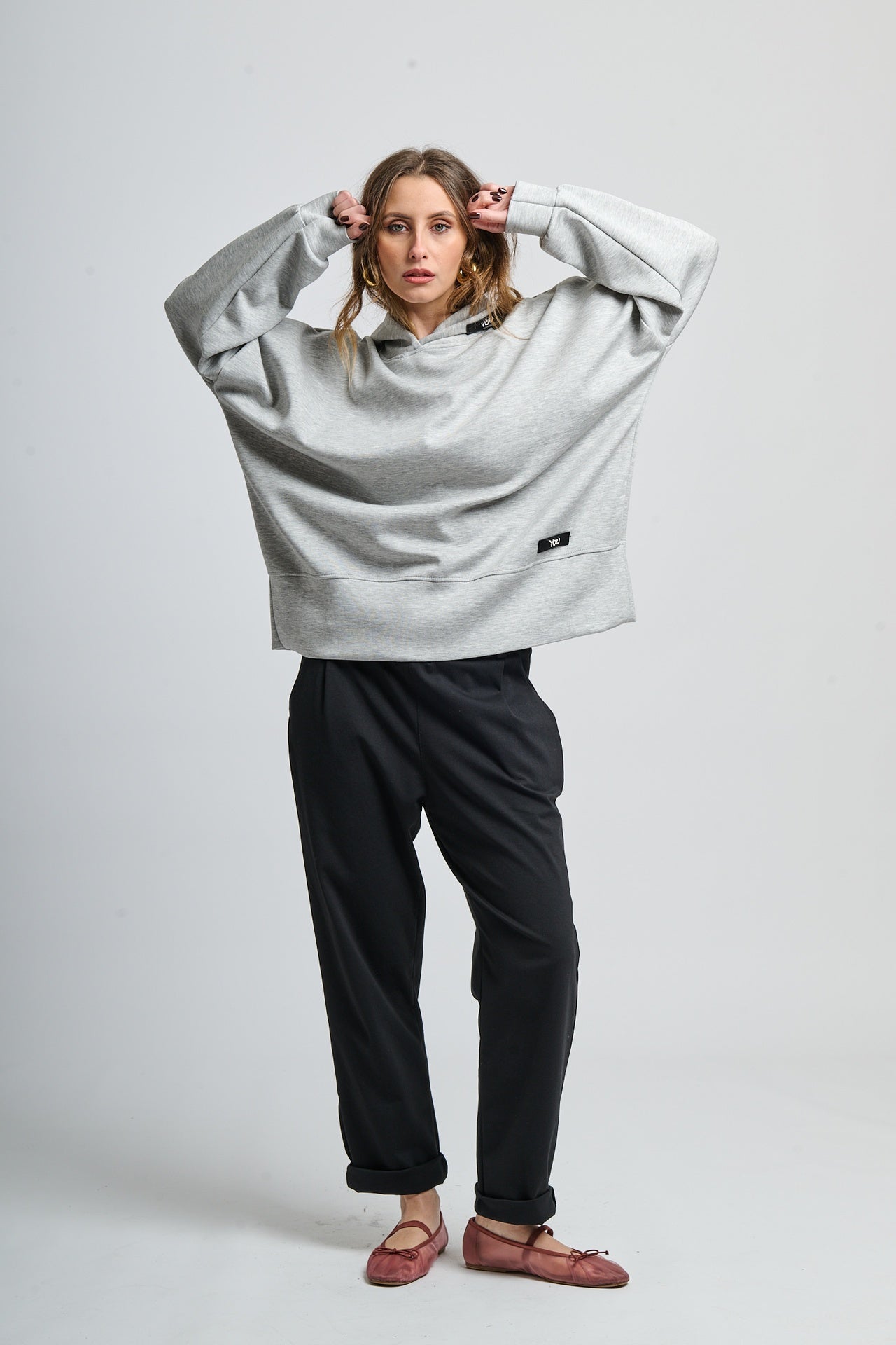 Outfit con felpa grigia con cappuccio e pantaloni neri, look minimale