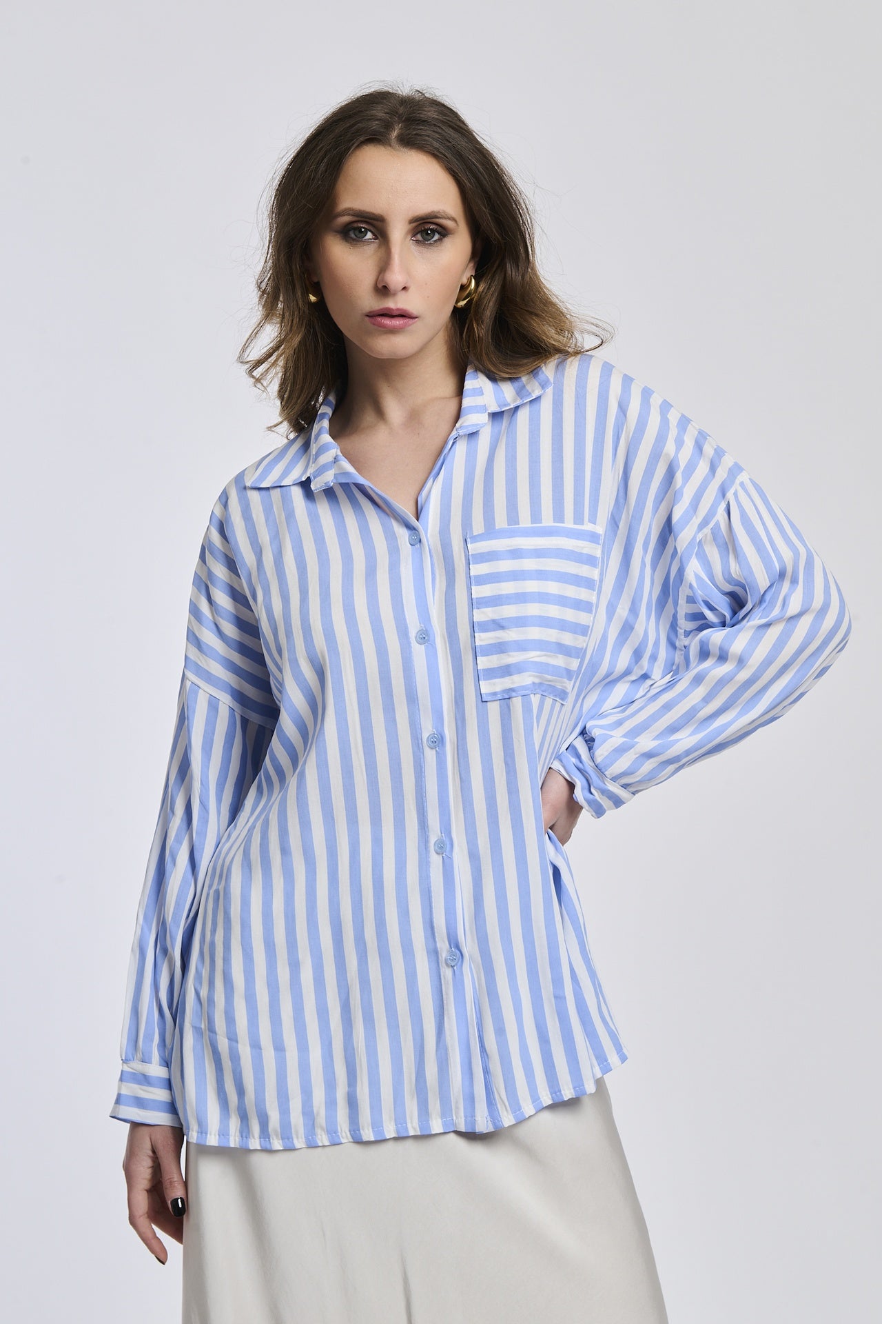 Donna con camicia a righe azzurre, dettagli suturali puliti, che conferisce un’eleganza minimalista.