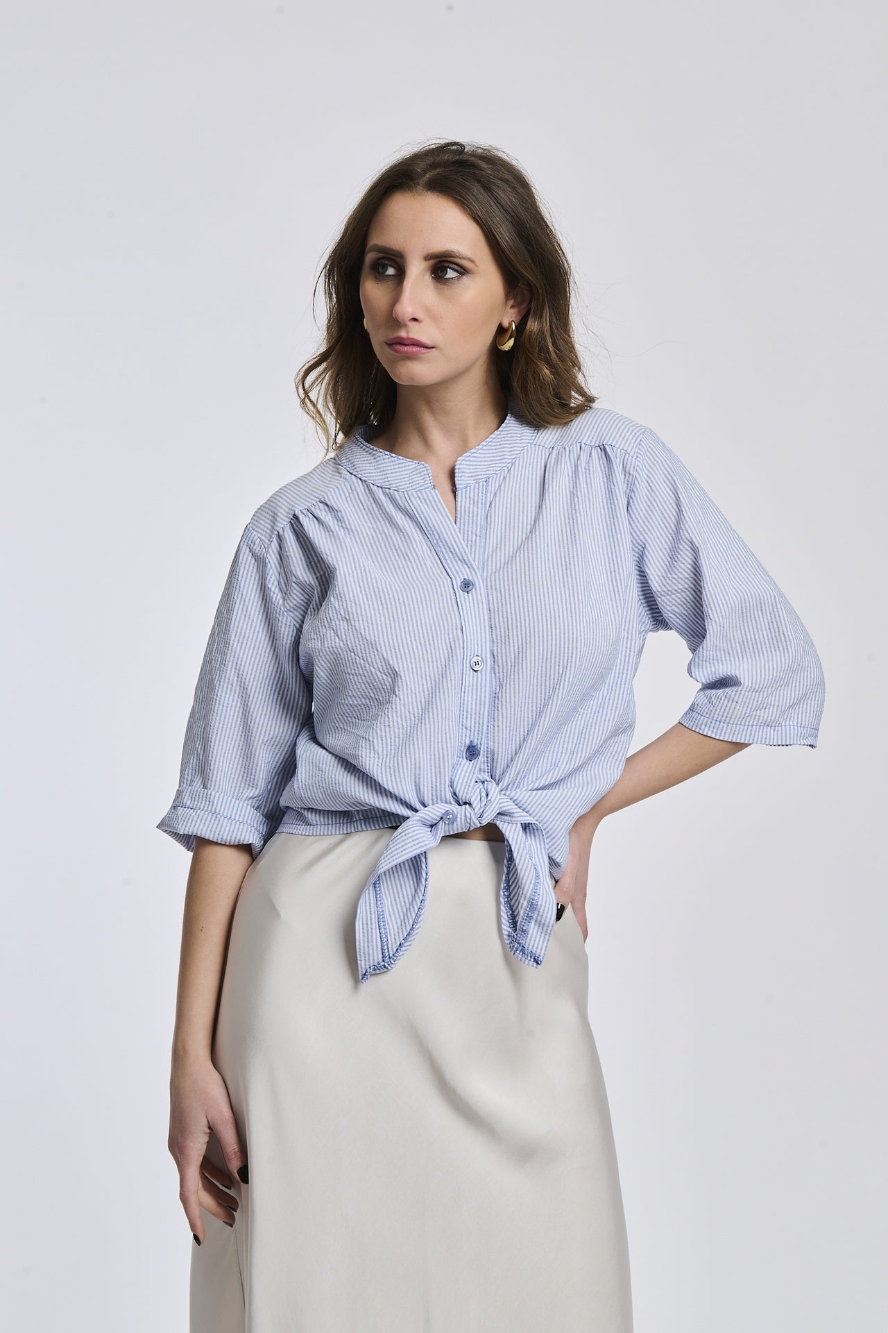Camicia a righe navy e bianche da donna, nodo sul petto, che valorizza la silhouette con eleganza.