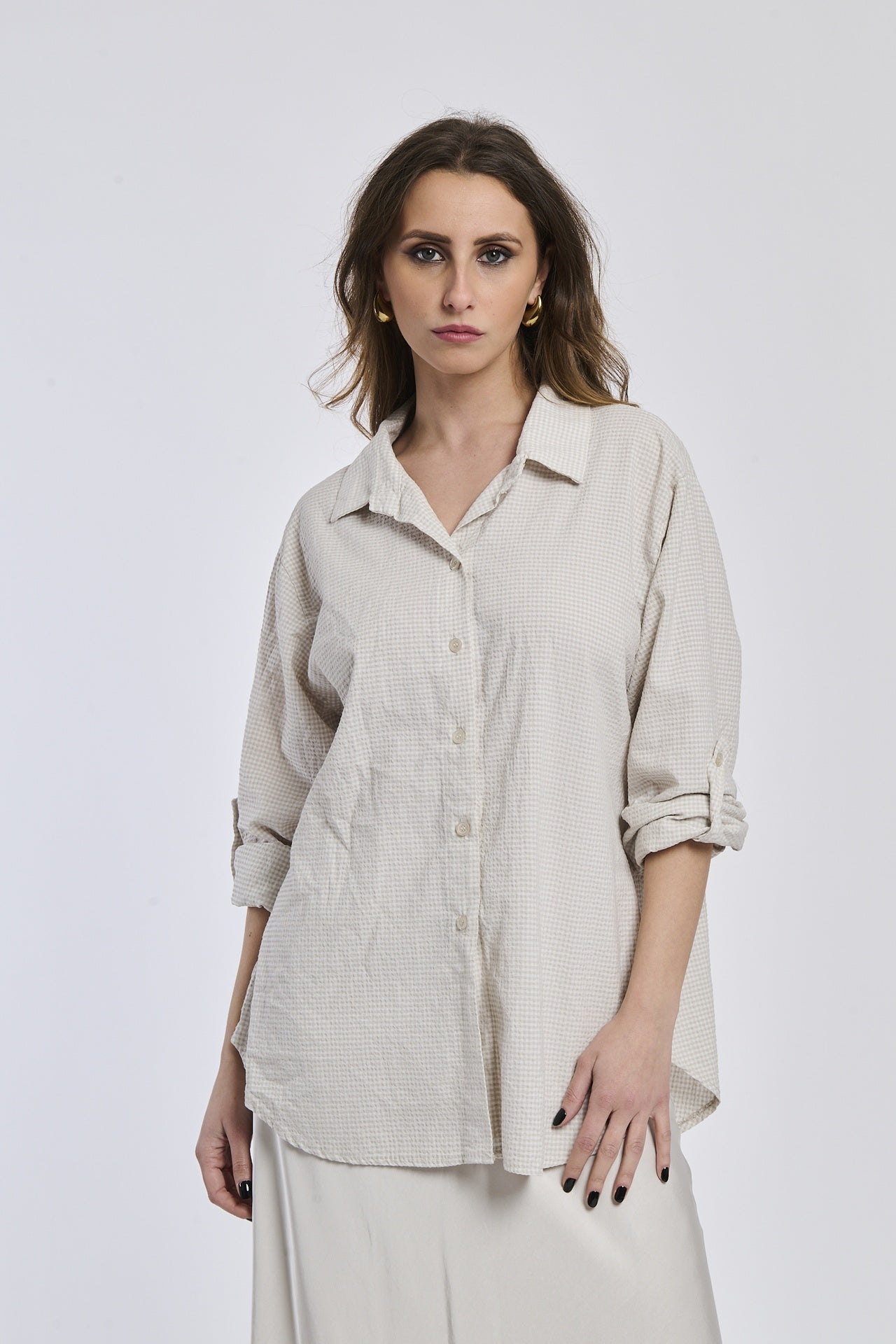 Camicia beige a righe, collo camiciera, maniche a 3/4, abbinata a pantaloni chiari.