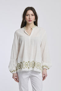 Ragazza indossa una giacca marrone di lana con maniche lunghe e collo a camicia, taglio regolare e bottoni in legno, abbinata a una gonna nera, creando un look elegante e caldo per l'autunno.