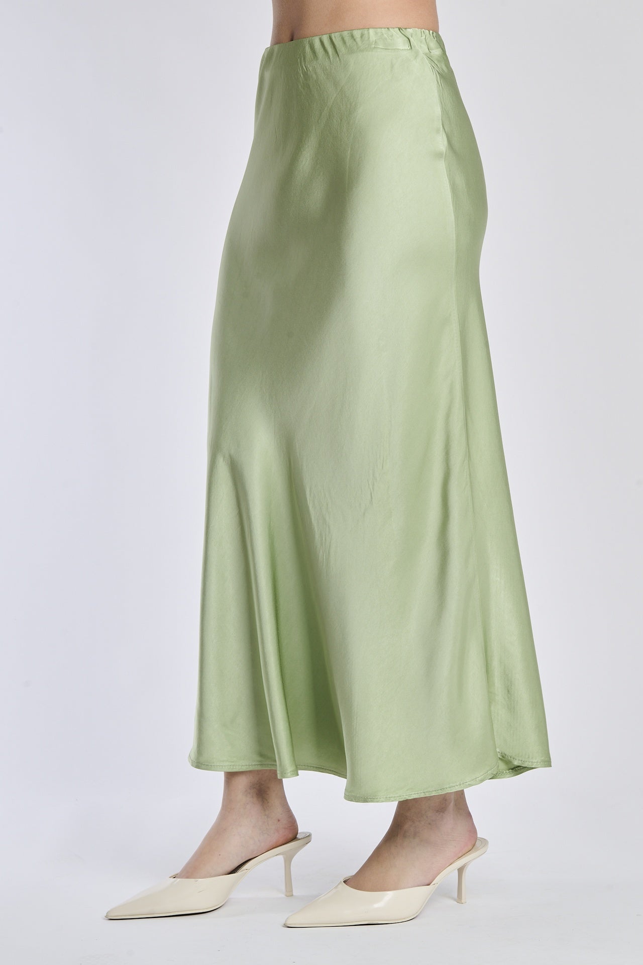 Gonna verde in raso lucido, vista frontale con scarpe alti tacchi