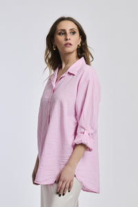 Camicia rosa a righe, collo camiciera, maniche a 3/4, abbinata a pantaloni chiari.