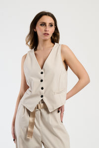 Completo beige su una modella: gilet a bottoni e pantaloni, combinazione classica e versatile.