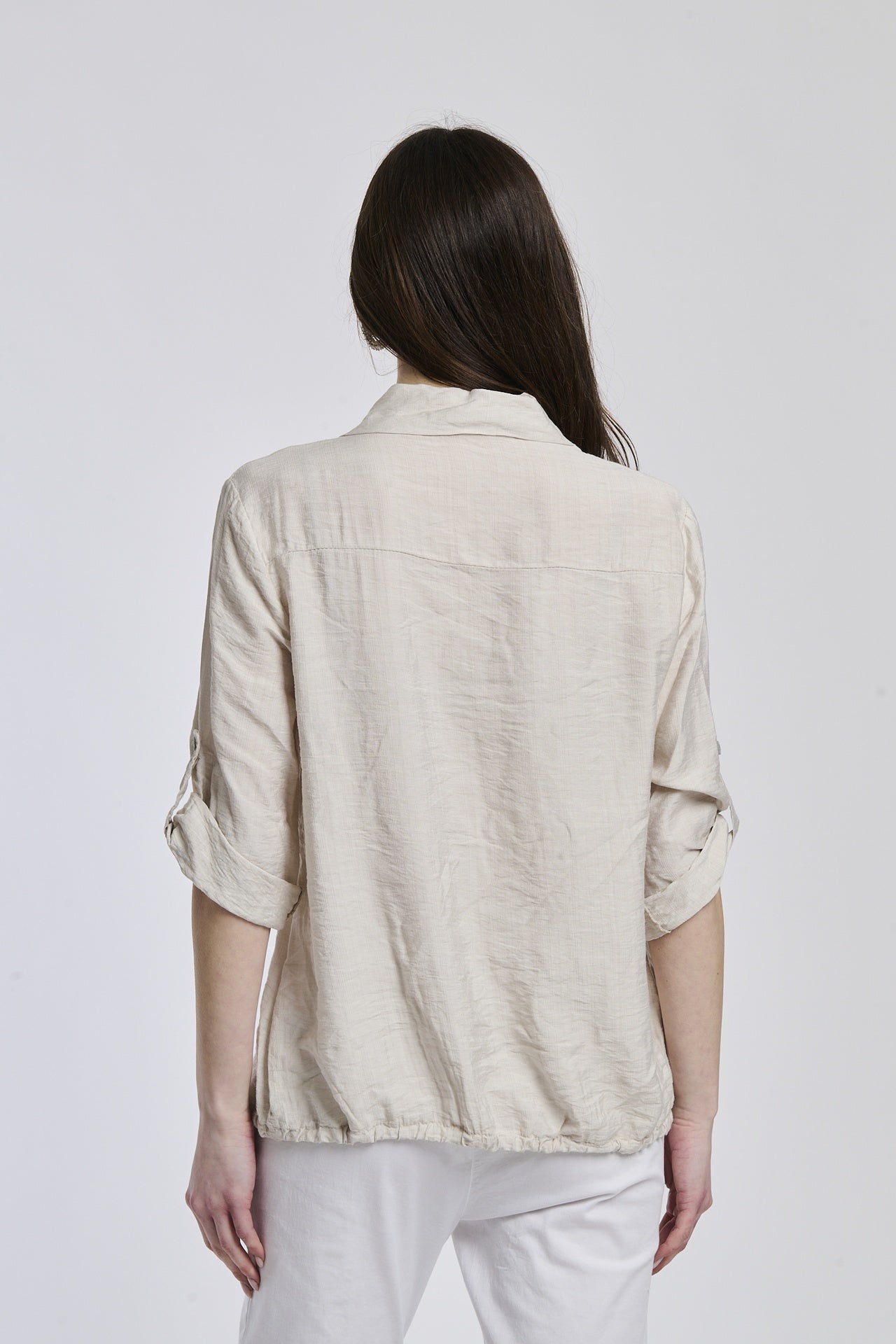 Donna indossa una camicia beige di lino, con tasche sul petto, perfetta per un outfit informale.