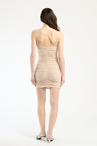 Abito beige stretch su una modella, perfetto per occasioni formali.