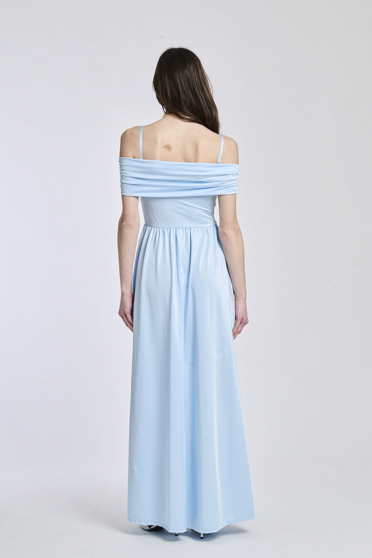 Abito azzurro a spalline scollate, taglio fluido, fascia in vita che accentua la silhouette.