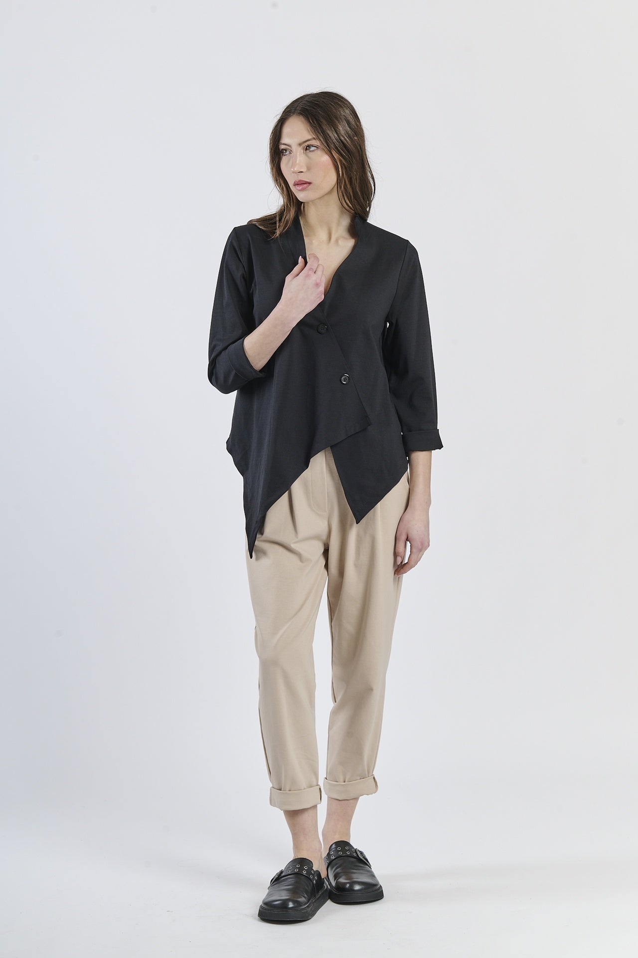 Outfit con camicia nero asimmetrica e pantaloni beige chiari, scarpe mocassini scure